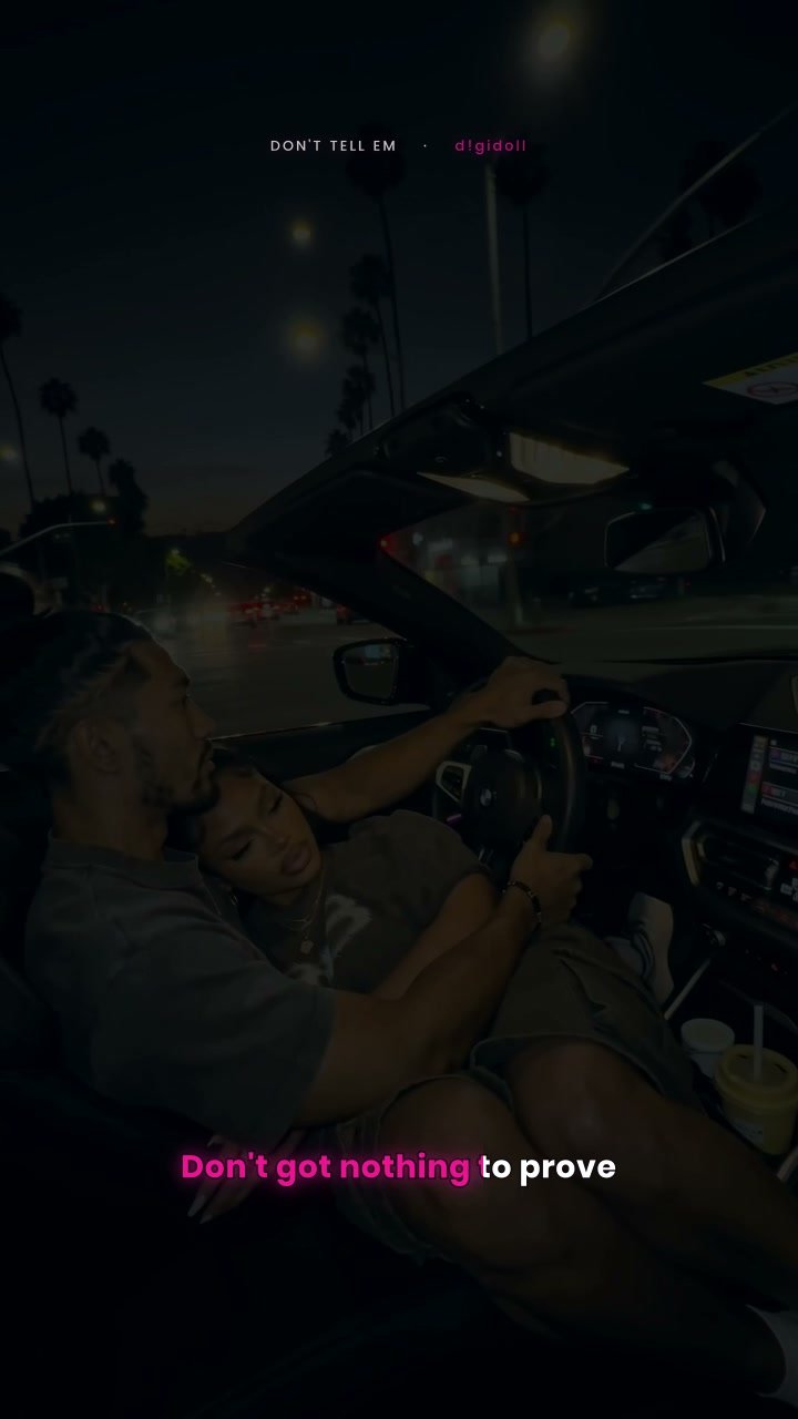Still from the Don't Tell Em music video: a couple in a convertible at night
